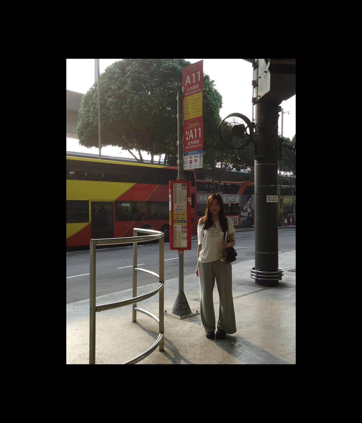 Amy standing at a bus stop, framed